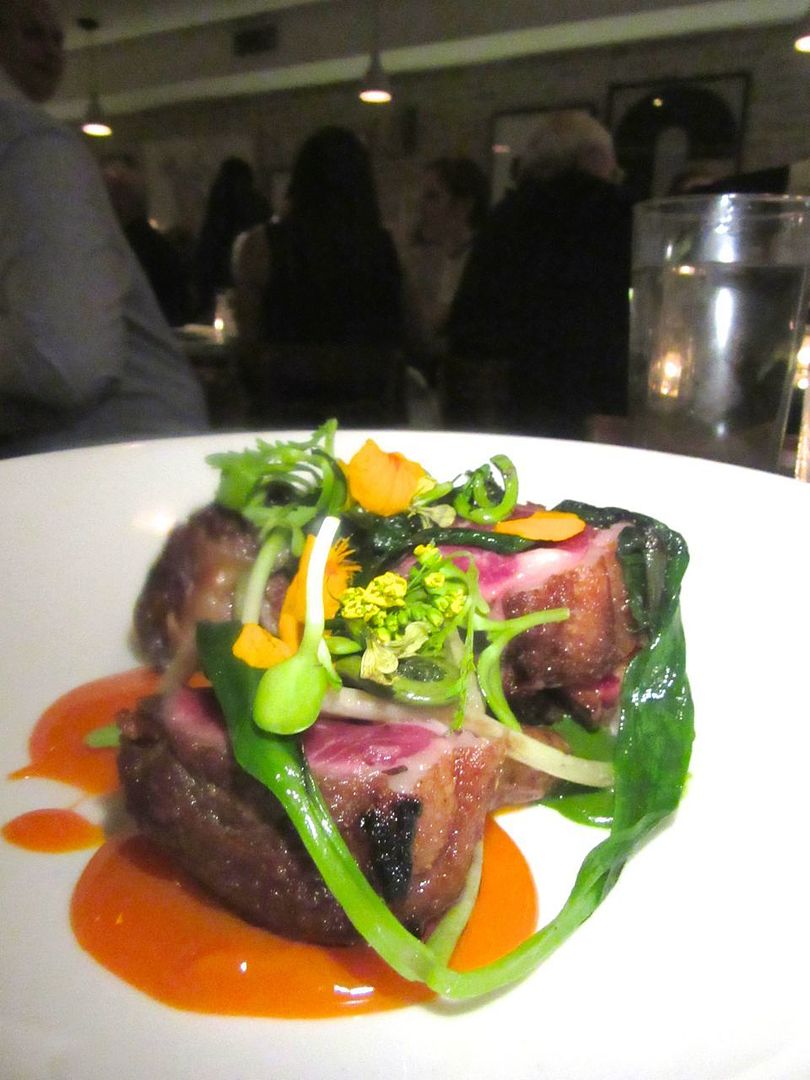 Three thick rounds of lamb loin wear jewels of ramp, fiddleheads, lamb bacon and flowers.