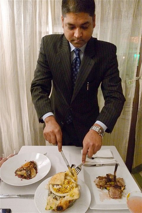The captain of our fate cuts open the baked-on bread cover of our jackfruit biryani.